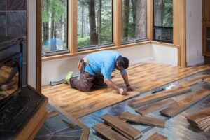Man installing wood flooring in home.