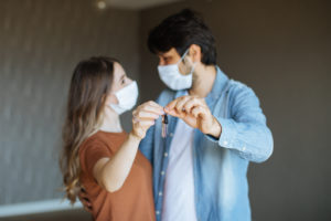 Couple with Face Masks Holding Keys to Their New Arlington Heights Apartment