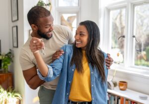 Happy African American couple joyfully holding keys to their new home. 
