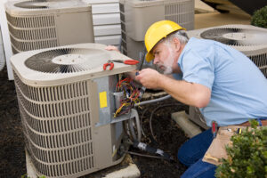 A man in a hard hat engaged in maintenance work on an air conditioner.