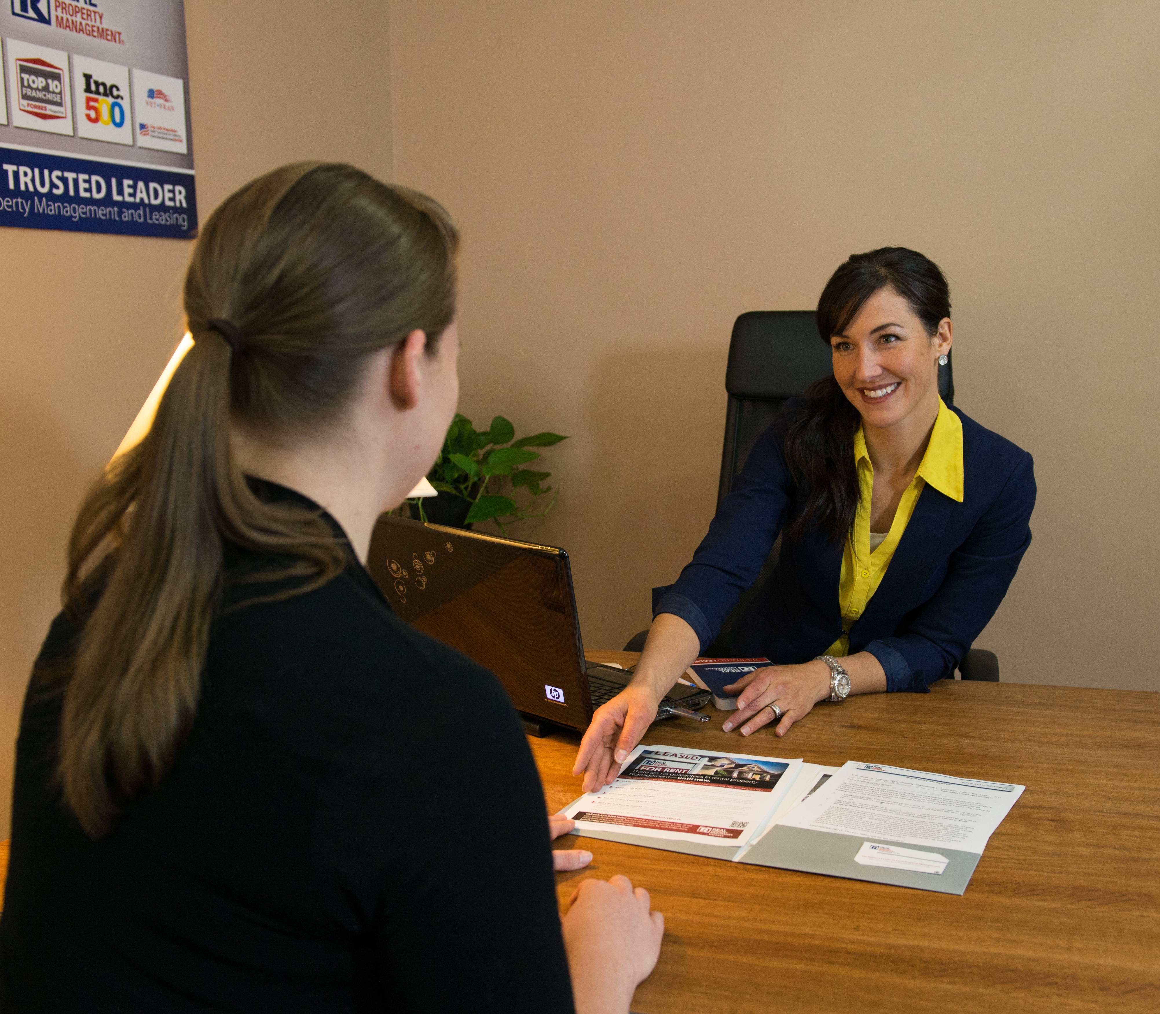 A Potential Resident Sitting at a Desk with a Real Property Management Executives Greater Atlanta Manager