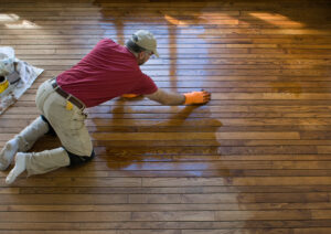 Carpenter staining a hardwood floor 