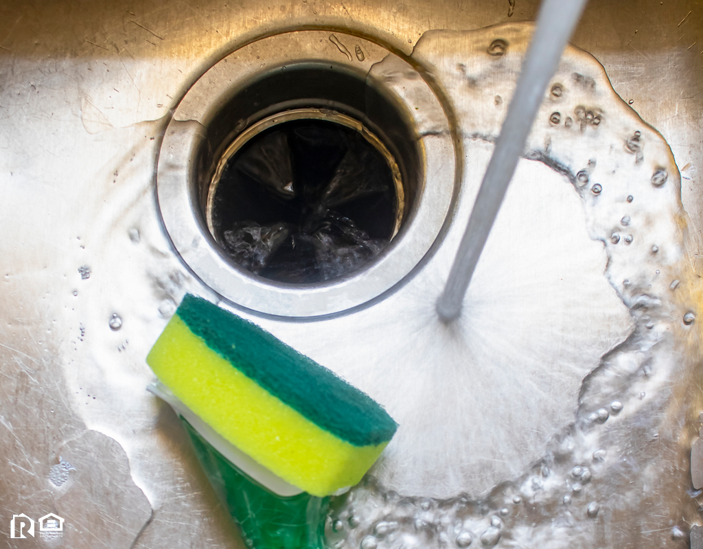 Water Running into a Sink with a Pot Scrubber Lying In It