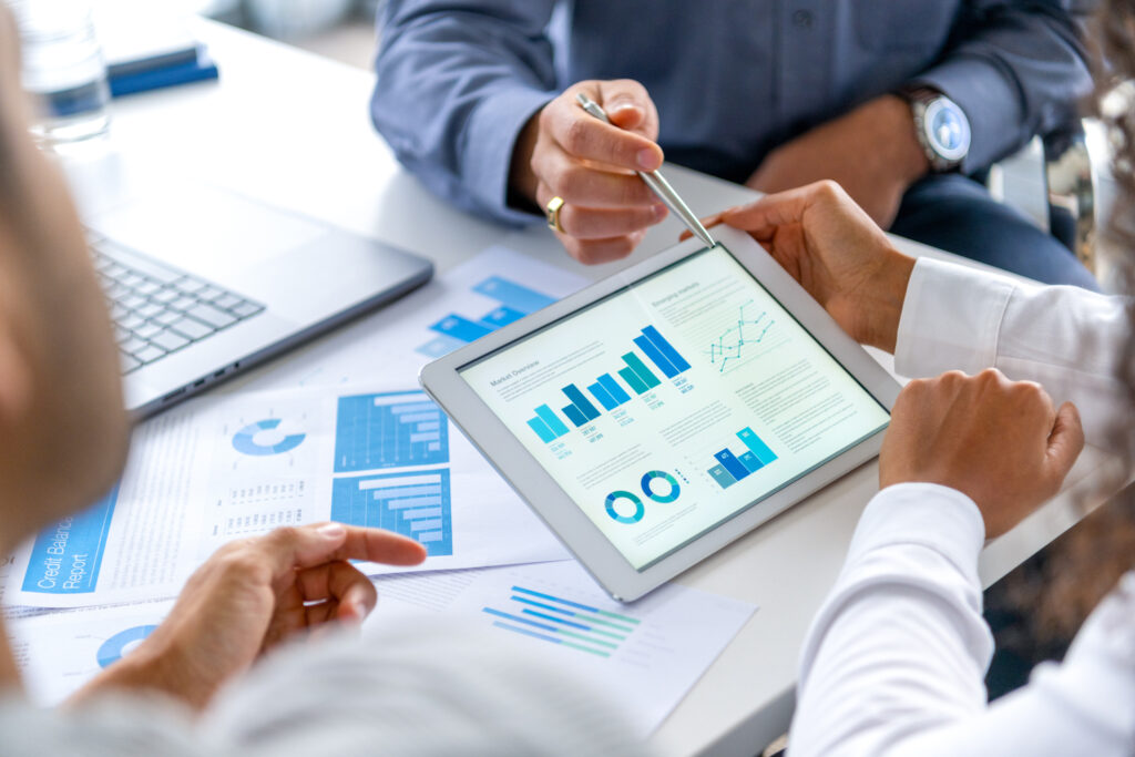 Real estate professionals analyzing rental market graphs on a tablet, collaborating to make data-driven decisions.