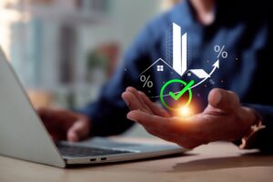 A man with a laptop displaying a green arrow and house icon, illustrating profitable real estate investment opportunities and market growth.