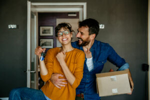 Excited renters holding their house keys and moving boxes.
