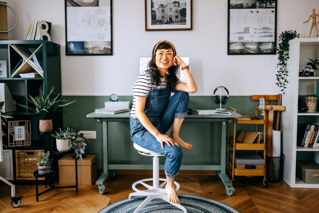 Cheerful, casually dressed woman sitting at the desk at home office.