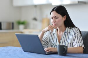 Suspicious landlord using a laptop to review rental applications.