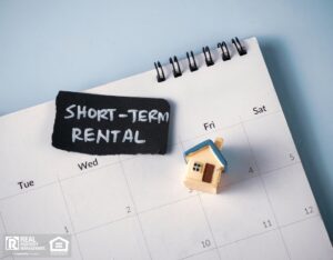 Calendar showing short-term rental dates with a house model and a sign indicating "Short Term Rental”.