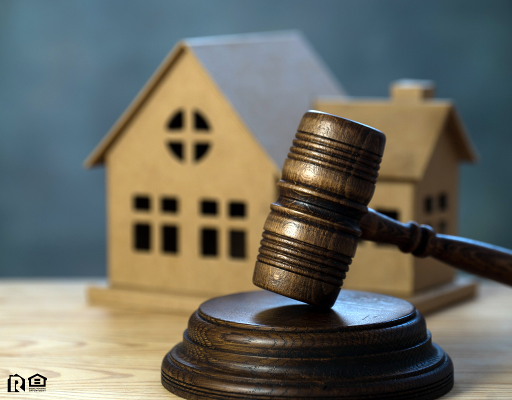 An Auction Gavel Propped Up in Front of a Replica of a House