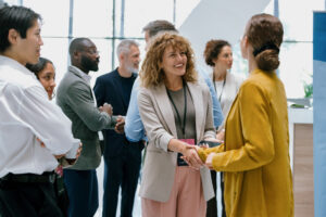 Business professionals shaking hands at a real estate networking event, exchanging ideas and building connections.
