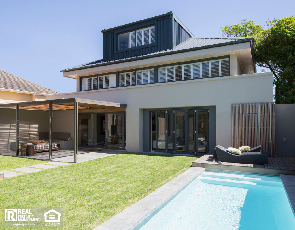A large house with a pool surrounded by a well-maintained lawn.