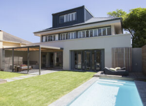 A large house with a pool surrounded by a well-maintained lawn. 