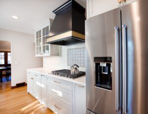 A modern kitchen equipped with a refrigerator and stove, displaying important appliances for everyday cooking.