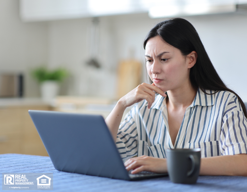 Suspicious landlord using a laptop to review rental applications.