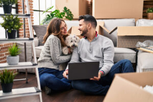 Man and woman using laptop sitting on floor with dog at new pet friendly rental 