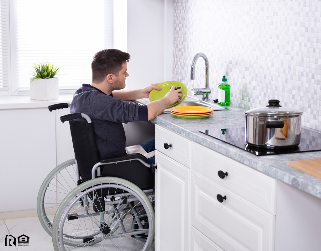 Lynbrook Cleaning Dishes in the Kitchen from His Wheelchair