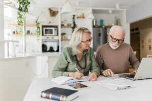 Senior couple going through property finances and using computer at home.