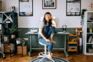 Cheerful, casually dressed woman sitting at the desk at home office.
