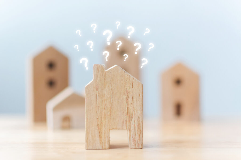A wooden house adorned with various question marks, symbolizing curiosity about a rental home.