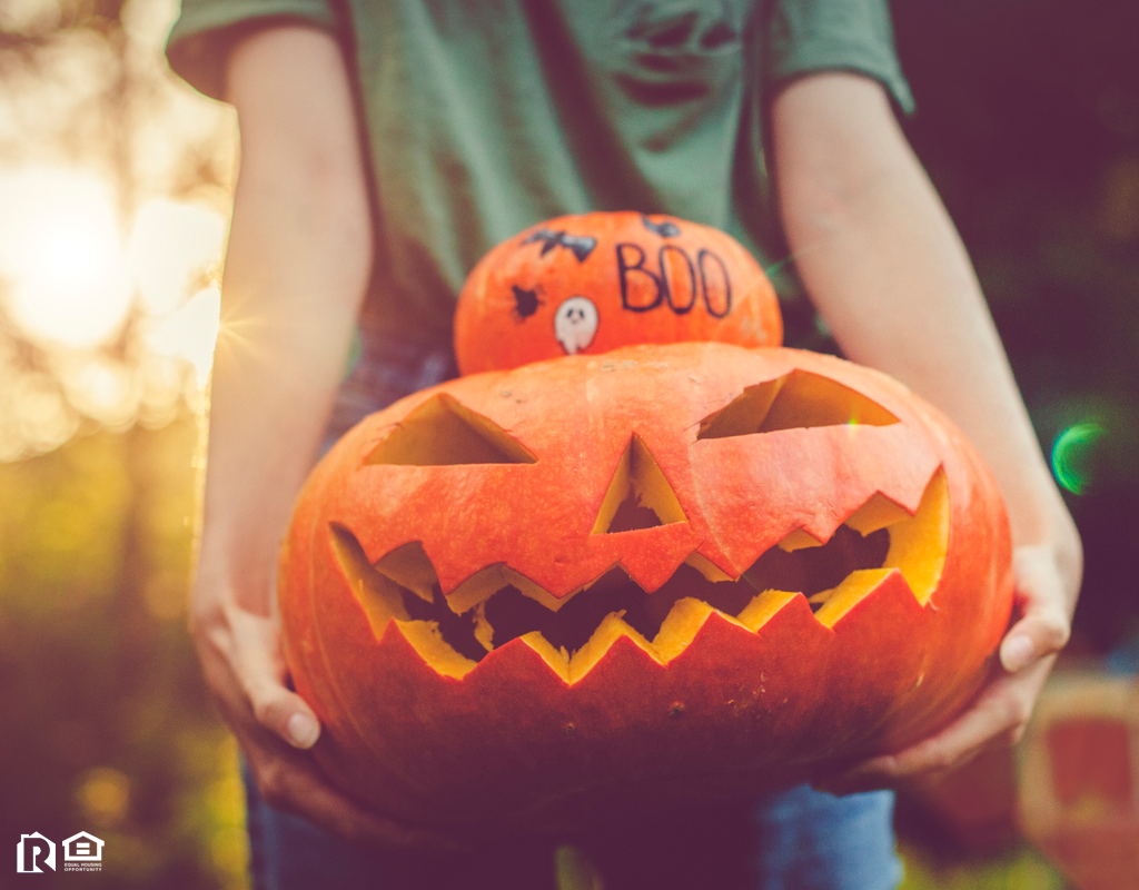 Dunnellon Resident Holding a Stack of a Decorated Pumpkin and a Jack-o-Lantern