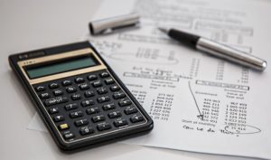 Calculator, paper and pen on a desk