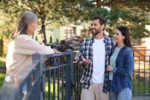 Young couple talking to senior woman near fence outdoors.