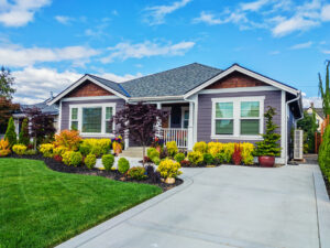 A charming house surrounded by a well-kept yard, featuring lush green grass and colorful flowers.