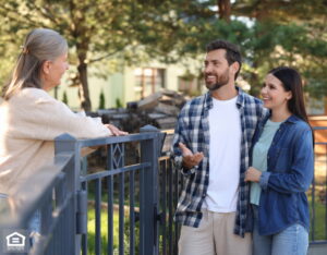 Young couple talking to senior woman near fence outdoors.