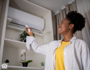 Woman turning on air conditioner with remote.