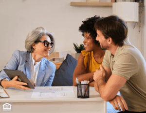 A property manager presenting investment information on a tablet to a young couple during a home consultation.