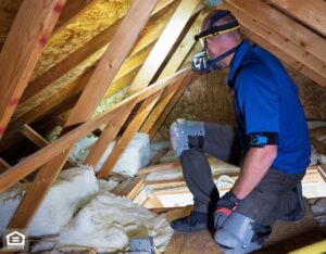 Home inspector kneels inside a finished attic of a residential property.
