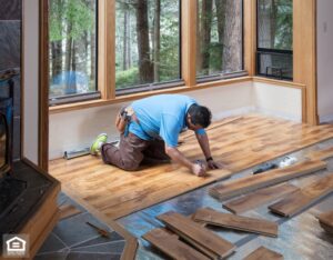 Man installing wood flooring in home.