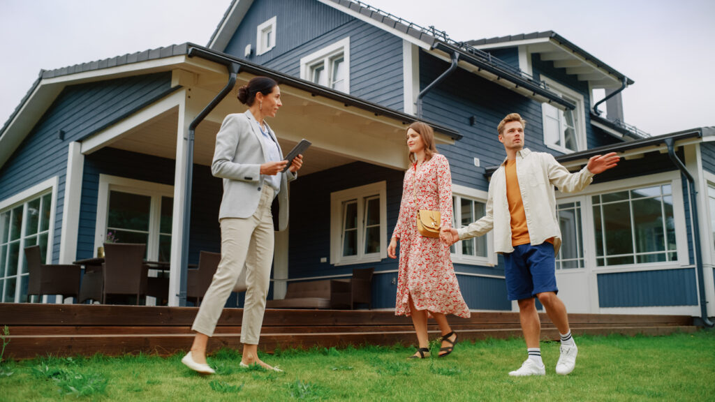 Young Couple Visiting a Potential New Home Property with Professional Real Estate Agent. real estate agent Showing a Beautiful Modern House with Traditional Suburban Design to a Young People. Slow Motion