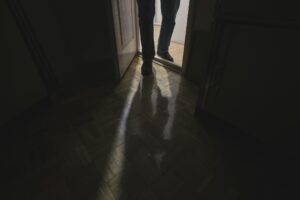 Suspicious person entering room with lights turned off.