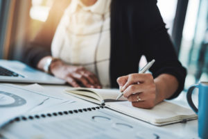 Cropped shot of a businesswoman making notes at her desk in a modern office.