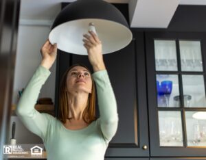 Woman installing an energy efficient light bulb into a chandelier.