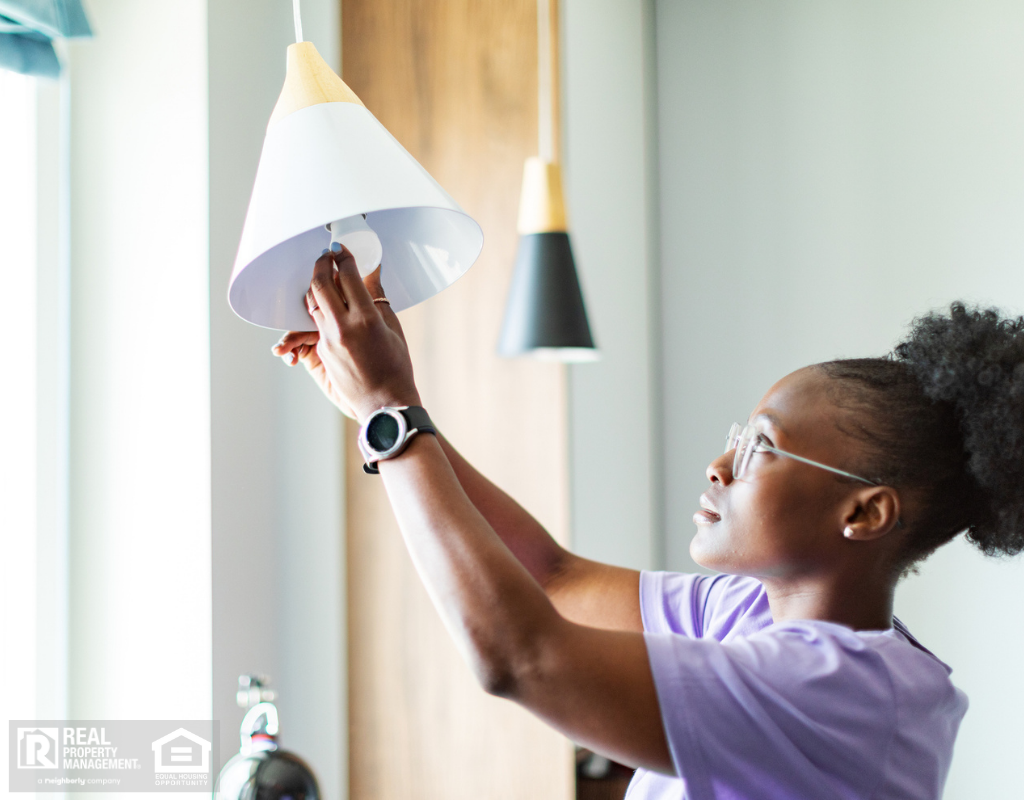 Young adult woman changing burnt out light bulb.