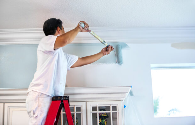 Lubbock Property Owner on Ladder Painting Interior Walls with Roller