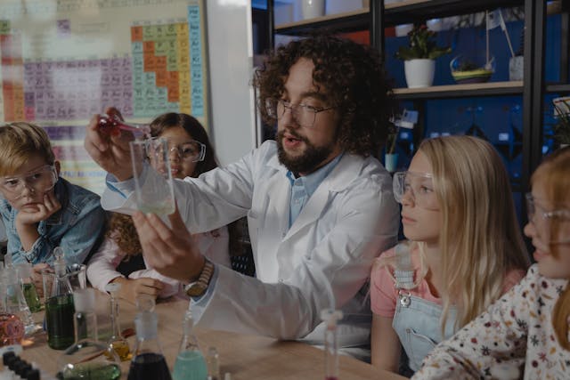 children being taught how to a science experiment by an adult