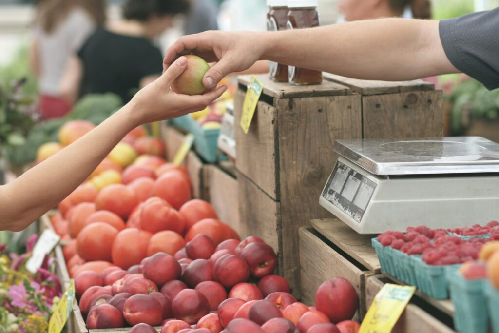 close-up of a person buying an apple at a farmer's market