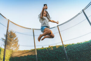 A kid joyfully jumping high in the air on a trampoline.