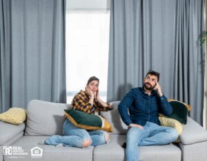 Young couple looking at the ceiling while concerned about noisiness from upstairs neighbor.