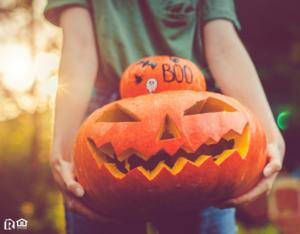 Conroe Resident Holding a Stack of a Decorated Pumpkin and a Jack-o-Lantern