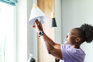 Young adult woman changing burnt out light bulb.
