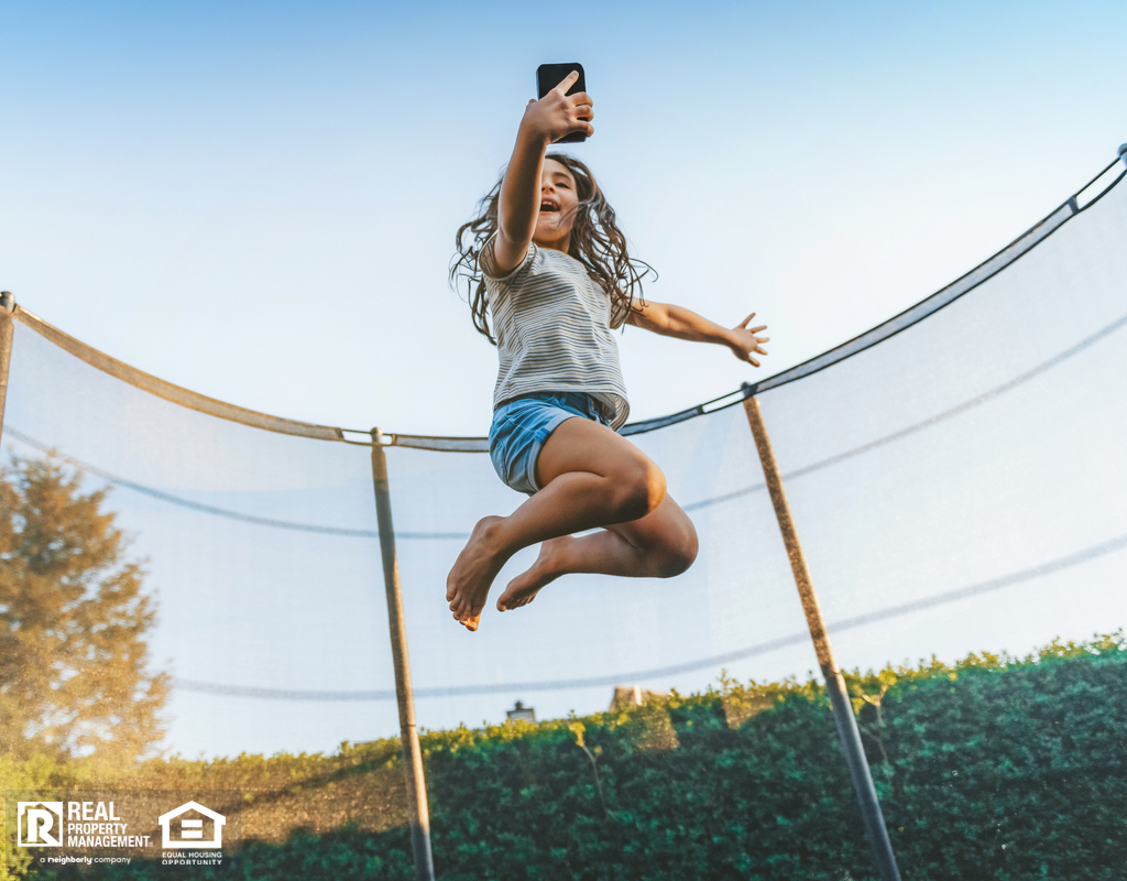 Little Girl Jumping on Trampoline in Backyard