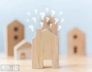 Questions Marks Hovering Above a Wooden Block in the Shape of a House