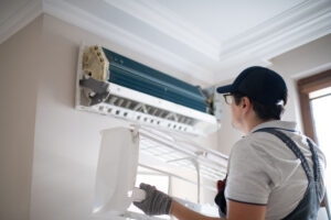 A man adjusting an air conditioner while upgrading the HVAC system.