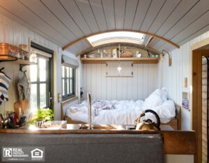 A cozy tiny home bedroom featuring a bed and a window, creating a bright and inviting atmosphere.