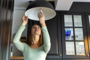 Woman installing an energy efficient light bulb into a chandelier.
